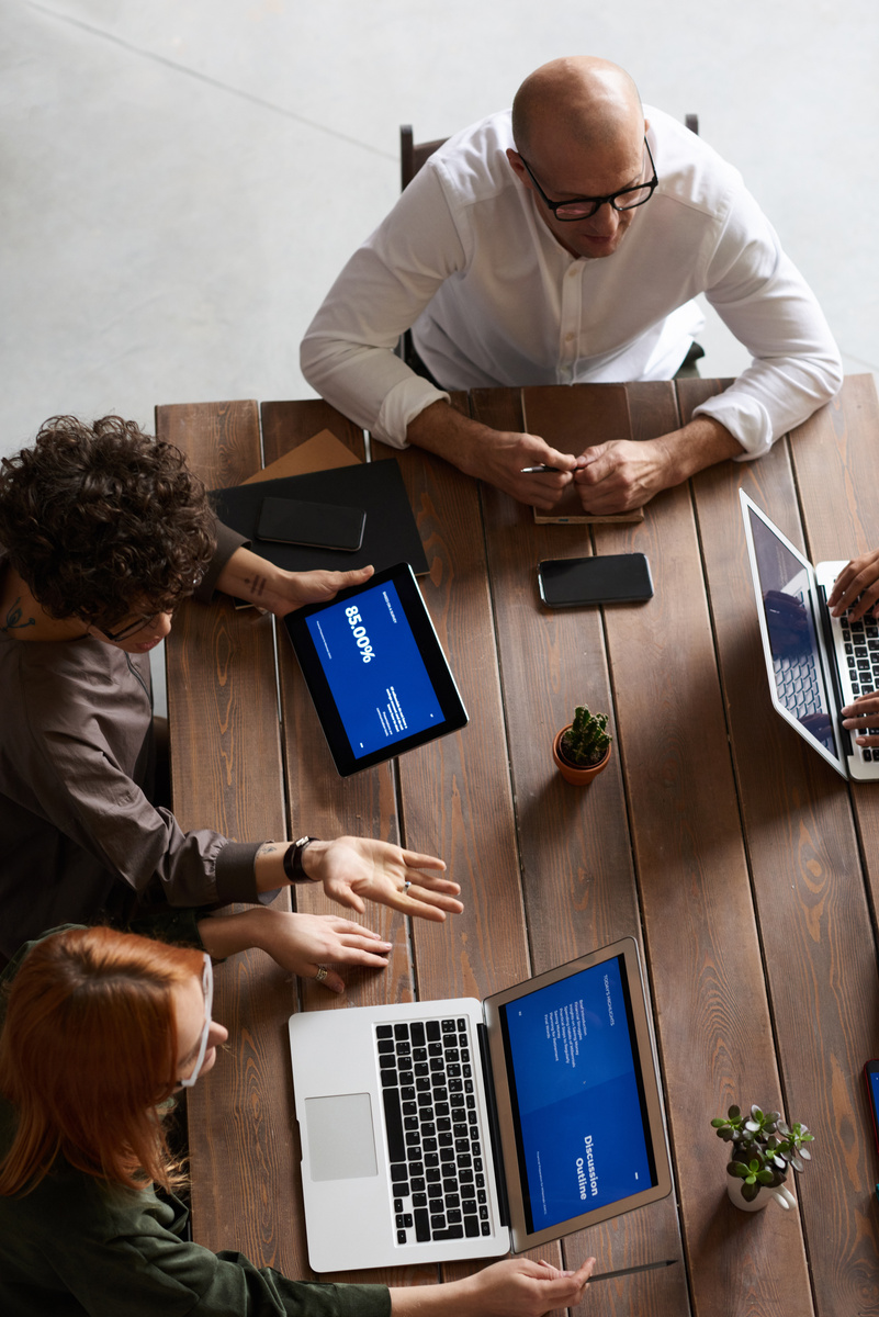 Diverse group of professionals in a meeting with laptops and a tablet